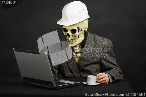 Image of Comical man in helmet and skeleton mask with computer