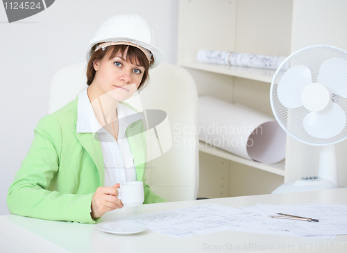 Image of Woman - a builder in helmet with cup in hand