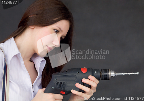 Image of Female student learns to use a drill