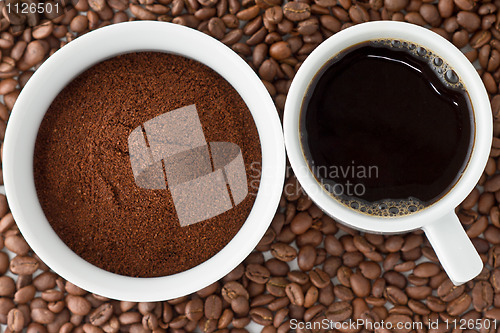 Image of Coffee power in bowl and coffee in cup on top of coffee beans