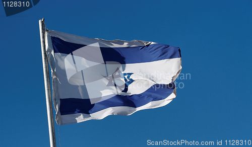 Image of Israel flag waving in the wind against a blue sky
