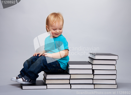 Image of Kid sitting on a a steps made of books