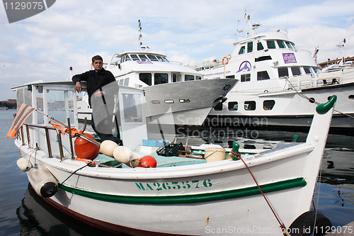 Image of MARSEILLE, FRANCE,  MARCH 6: a fisherman,  standing in his boat,  in the Vieux-Port, on Sunday, March 6th, 2011 in Marseille, France.