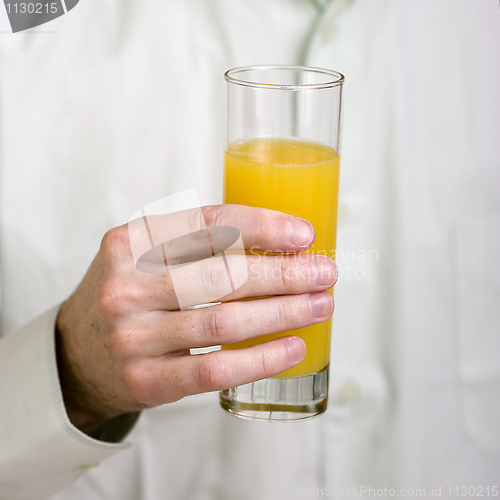 Image of Glass with orange juice in a hand