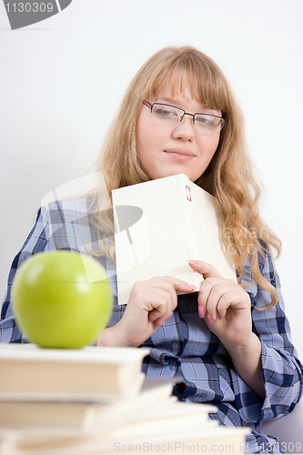 Image of The girl with the book looks at an apple