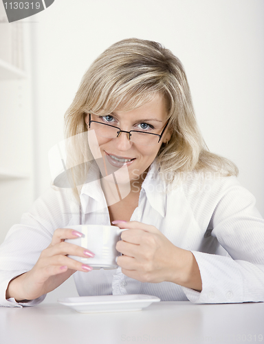 Image of The young woman drinks tea or coffee