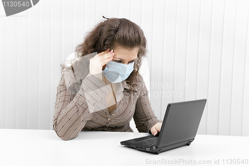 Image of The young woman in medical mask with the laptop