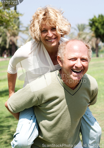 Image of Senior man giving piggy ride to her wife