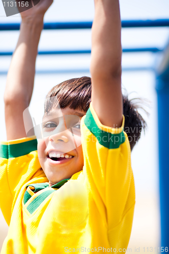 Image of Young kid hanging on jungle gym