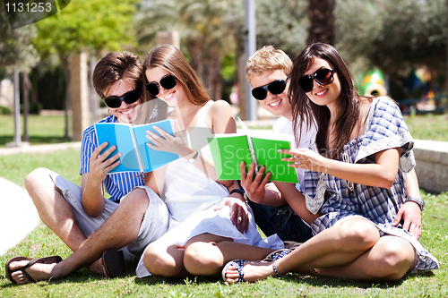 Image of Young couples relaxing in park and reading books