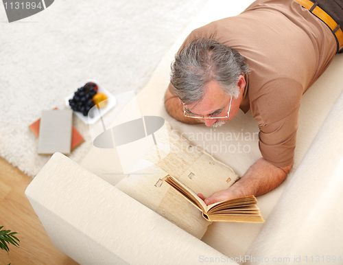 Image of Senior man relaxing and reading