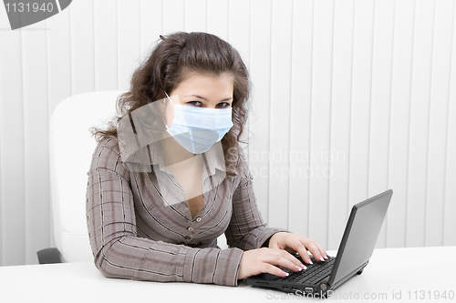 Image of The young woman in medical mask with the laptop