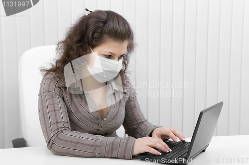 Image of The young woman in medical mask with the laptop