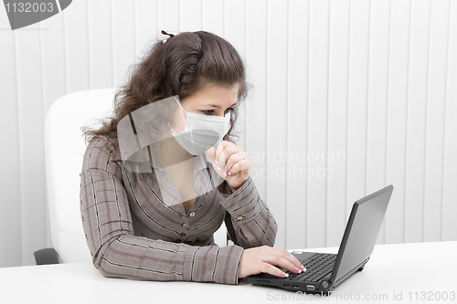 Image of The young woman in medical mask with the laptop