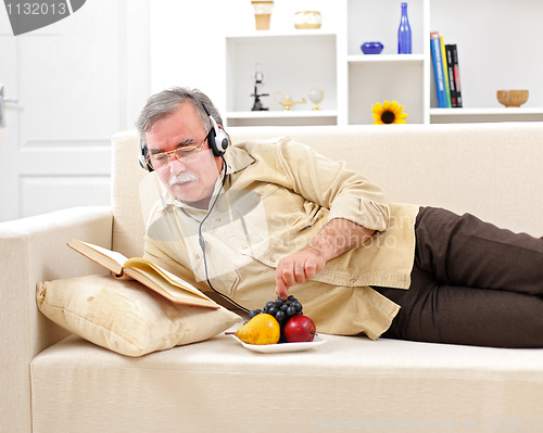 Image of Senior man relaxing and reading