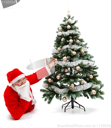 Image of Santa Claus laying and showing decorated christmas tree