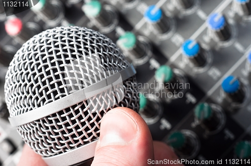 Image of Part of an audio sound mixer with microphone in hand