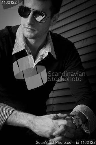 Image of Young man sitting in the window with sunglasses in black and whi