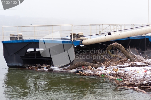 Image of Polluted shore with jetty and garbage in the fog