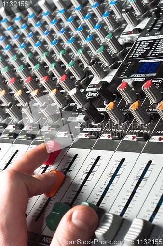 Image of Closeup of an audio sound mixer with the hand of a man