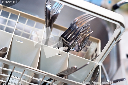 Image of Forks and knives in washing machine with blurry background