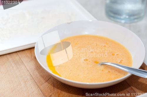 Image of Egg in plate on wooden board with flour in background