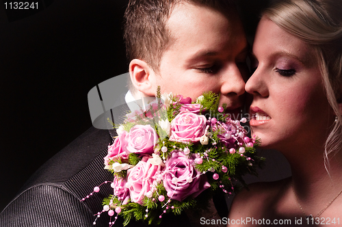 Image of young couple in wedding wear with bouquet of roses