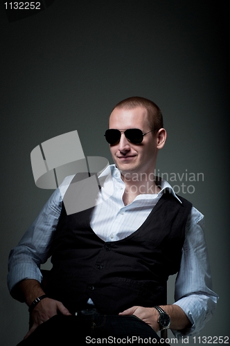 Image of Young man sitting in chair smiling in sunglasses