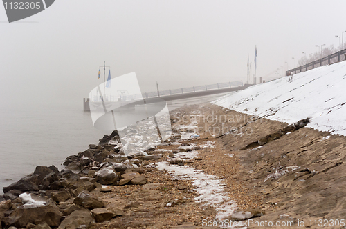 Image of Dirty shore in the fog with jetty in the background