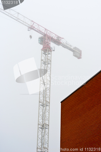 Image of Red bwall made out of brick with construction crane in backgroun