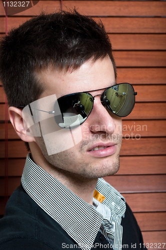 Image of Close-up of a young man in sunglasses against blinds