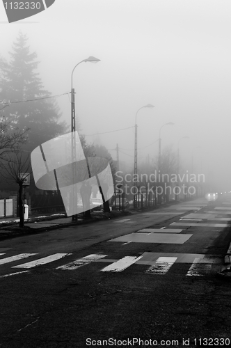 Image of Dark road in fog focus on crosswalk with  cars in the background