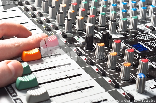 Image of Closeup of an audio sound mixer with the hand of a man