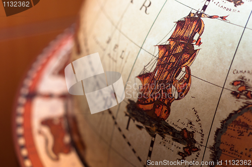 Image of Part of a globe with old ship on blurry background