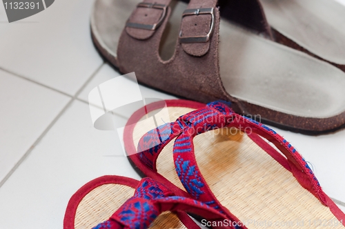 Image of Closeup of vietnamese and european slippers on white floor