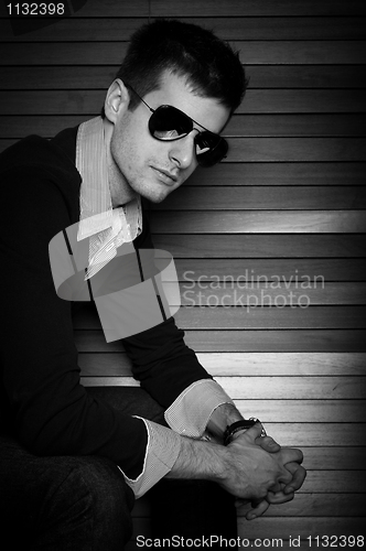 Image of Young man sitting in the window with sunglasses in black and whi