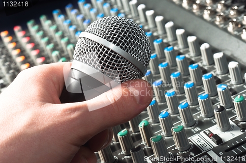 Image of Part of an audio sound mixer with microphone in hand