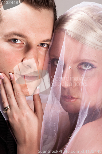 Image of Young bride in veil holding the chin of the groom