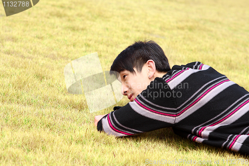 Image of Young man lying on grass 