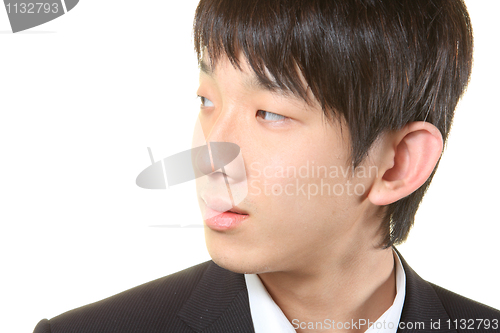 Image of Young businessman standing and looking right,