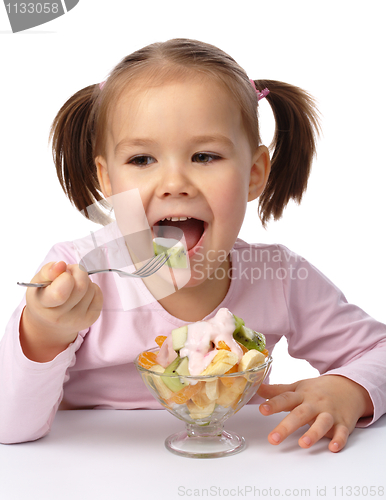 Image of Little girl eats fruit salad