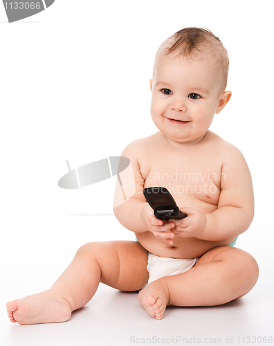 Image of Happy little baby plays with mobile phone
