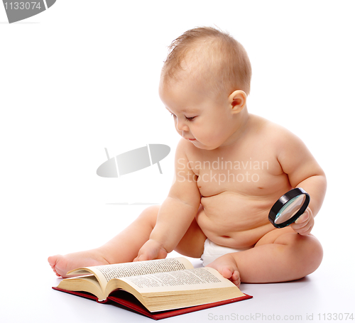 Image of Little child play with book and magnifier