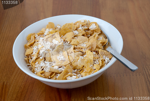 Image of White bowl with a spoon, corn and oats flakes