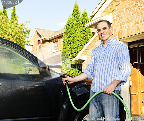 Image of Man washing car on driveway