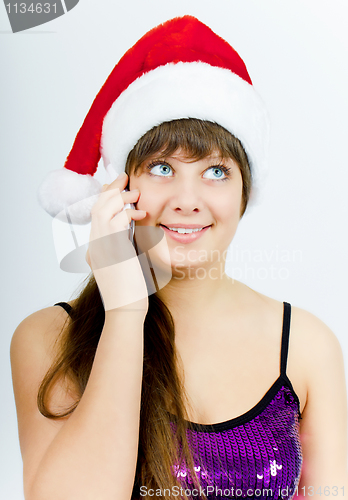 Image of happy smiling girl with Santa hat with a phone