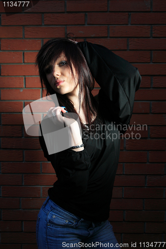 Image of fashion portrait of young woman with a brick wall