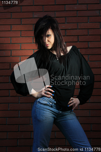 Image of fashion portrait of young woman with a brick wall