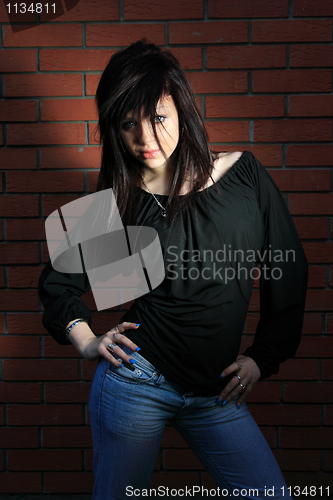 Image of fashion portrait of young woman with a brick wall