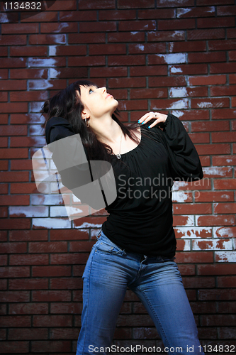 Image of fashion portrait of young woman with a brick wall